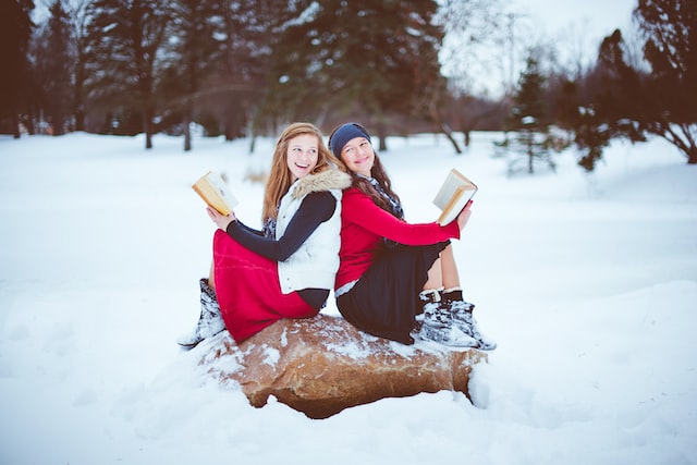 two girls sitting while holding books